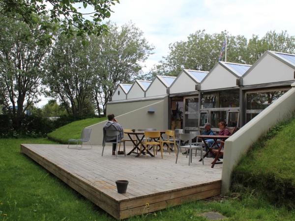 Tres personas sentadas en sillas en la terraza de una pequeña cafetería