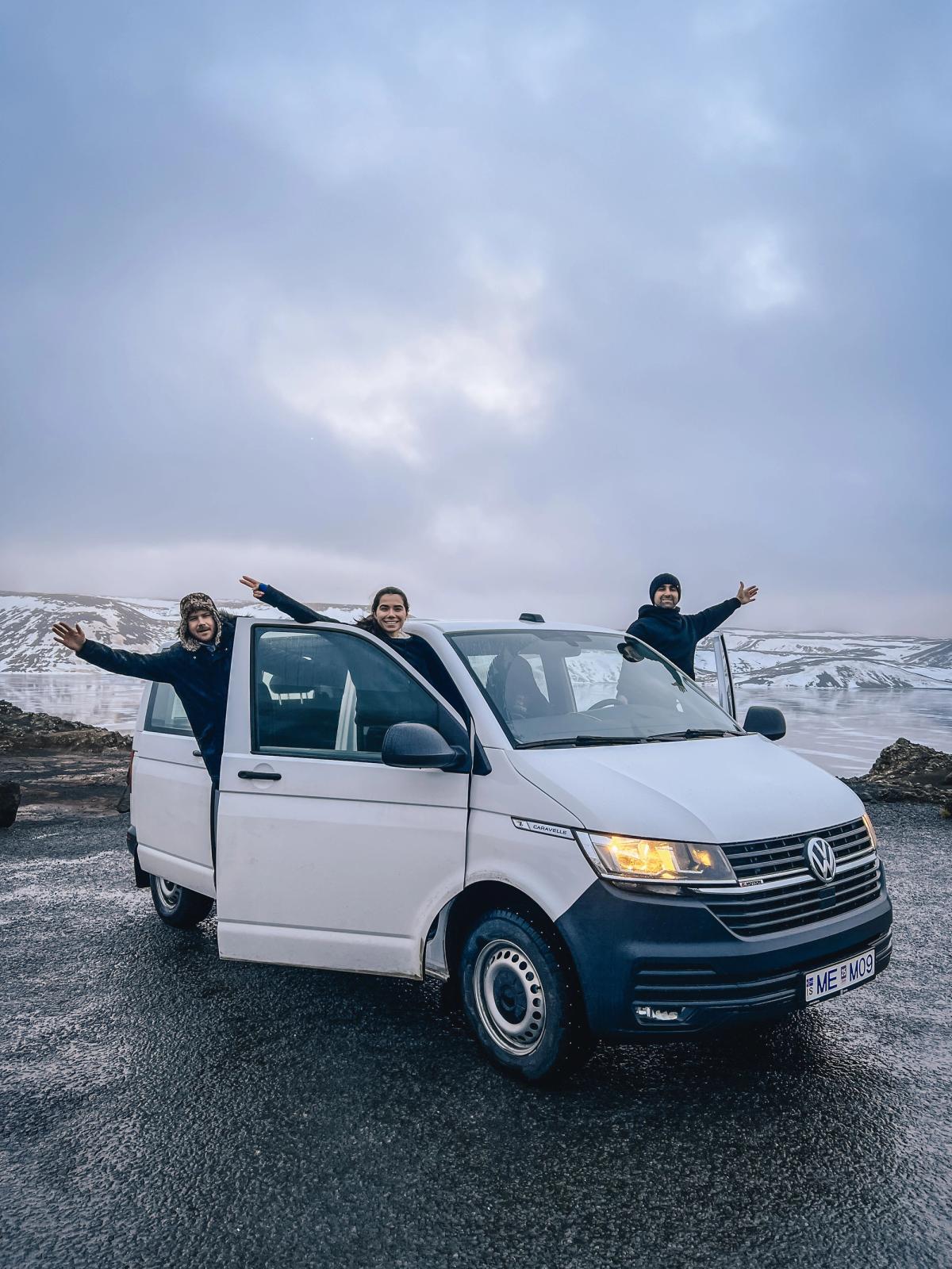 three people are standing in a white van with their arms outstretched
