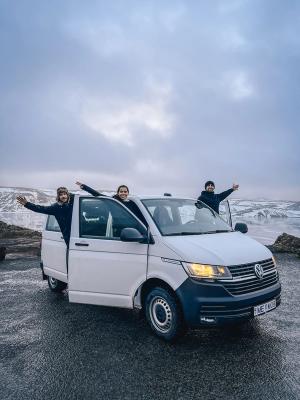 Minivan Rental Car Iceland three people are standing in a white van with their arms outstretched
