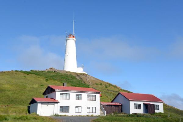 a lighthouse is sitting on top of a hill next to a house .