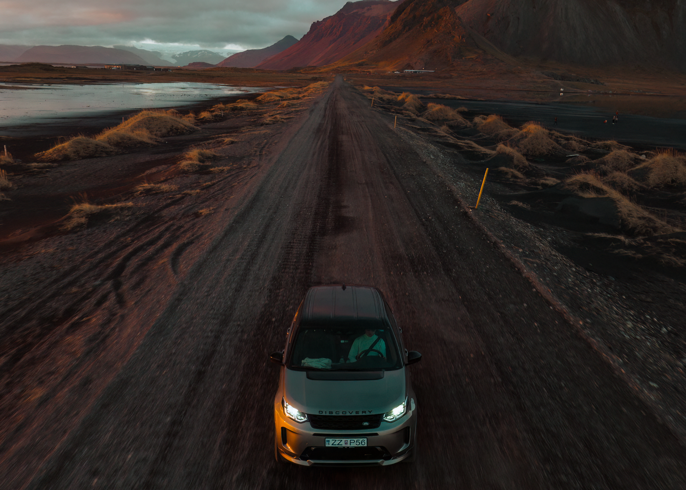 Ein Land Rover Discovery Sport 4x4 fährt auf einer Schotterstraße, vor ihm liegen Berge.