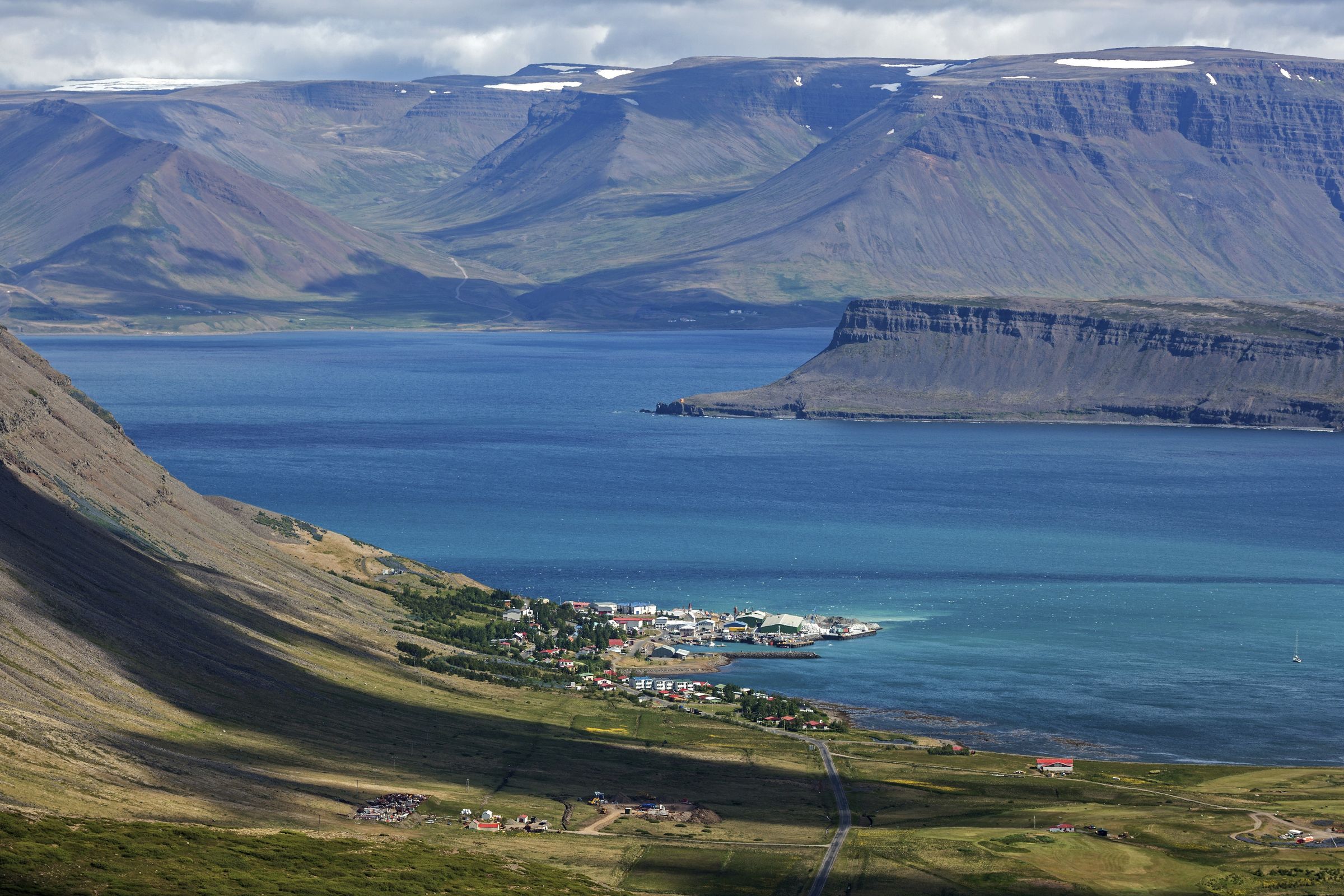 a large body of water surrounded by mountains and a small town .