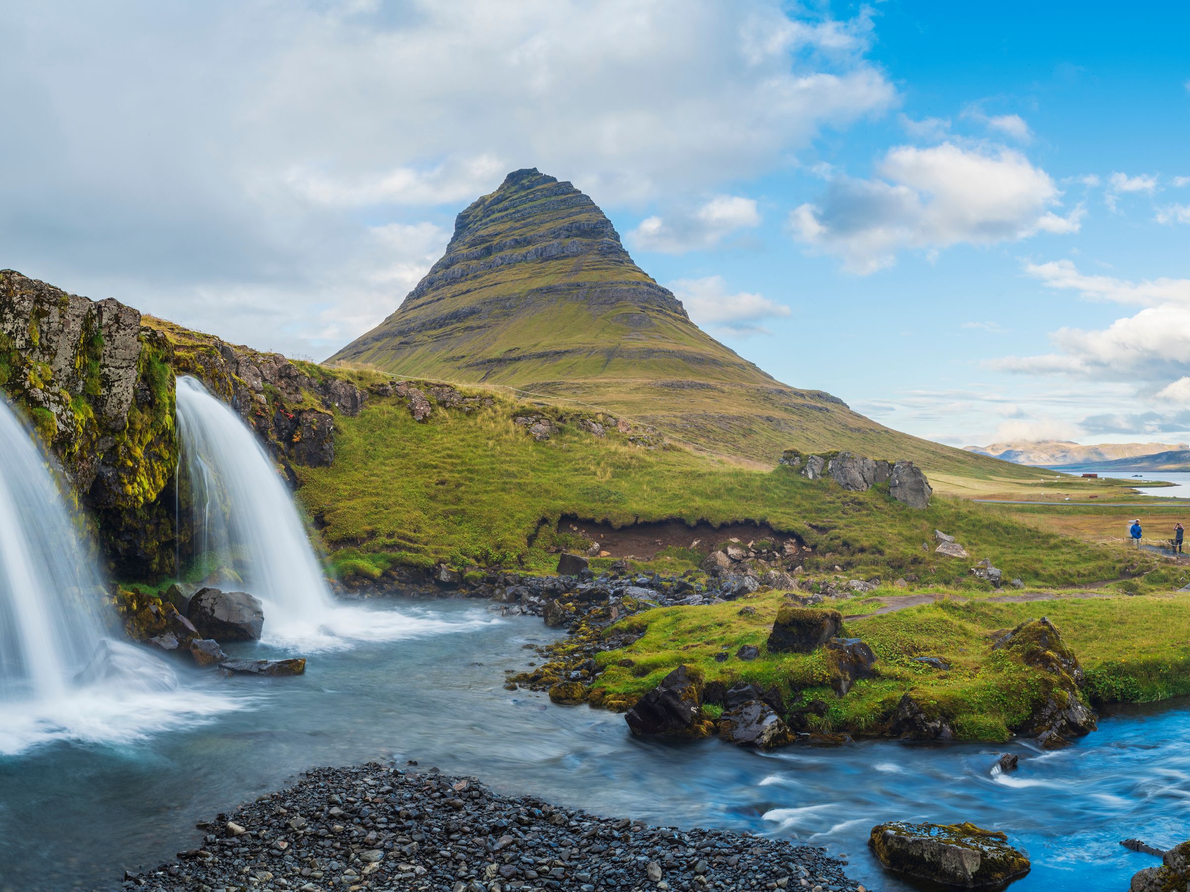 une cascade avec une montagne en arrière-plan au mont Kirkufell, dans la péninsule de Snæfellsnes en Islande.
