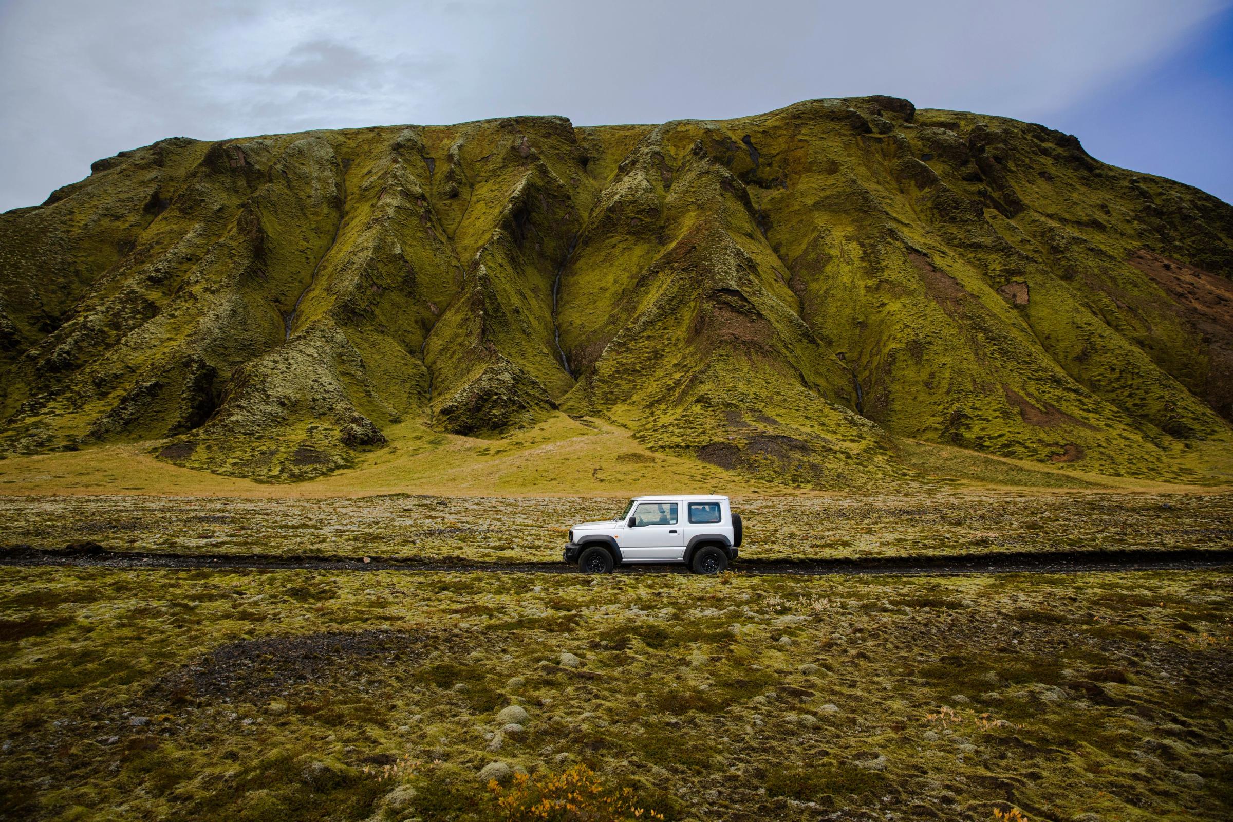 White car in Iceland with a mountain in the background