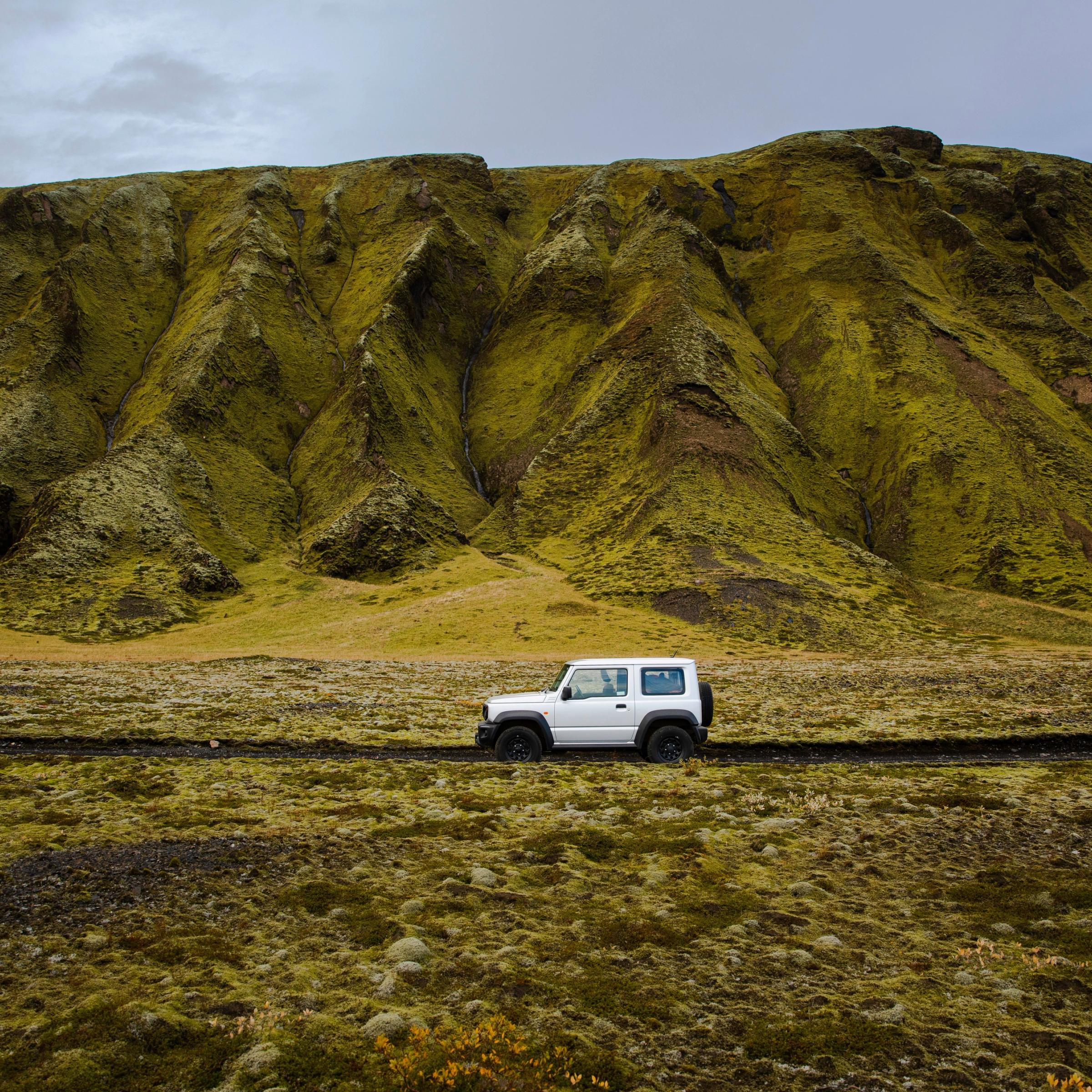 White car in Iceland with a mountain in the background