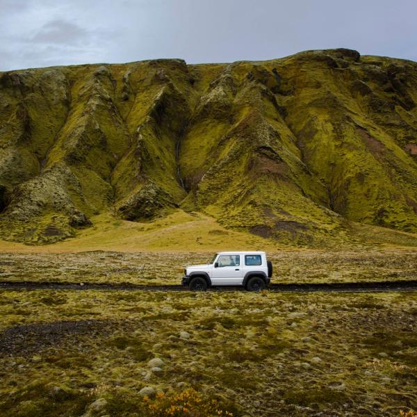 White car in Iceland with a mountain in the background