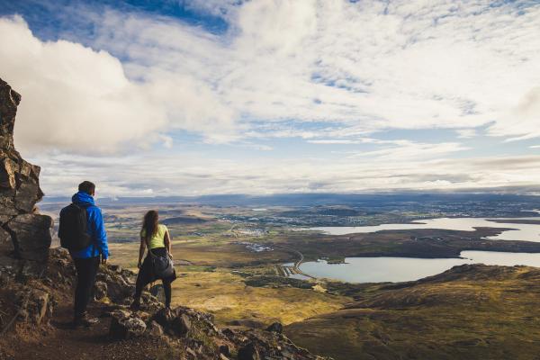un hombre y una mujer están de pie en la cima de una montaña mirando el paisaje .