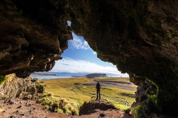 Loftsalahellir Cave iceland  man from the Loftsalahellir Cave and view on the Black sand beach  in Iceland