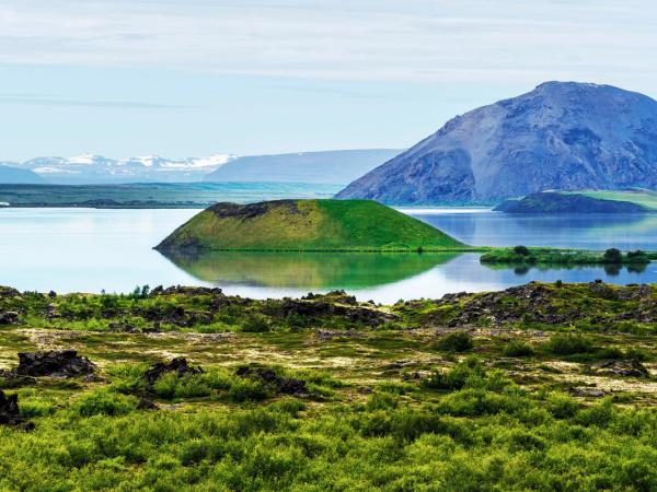 a small island in the middle of a lake with a mountain in the background .