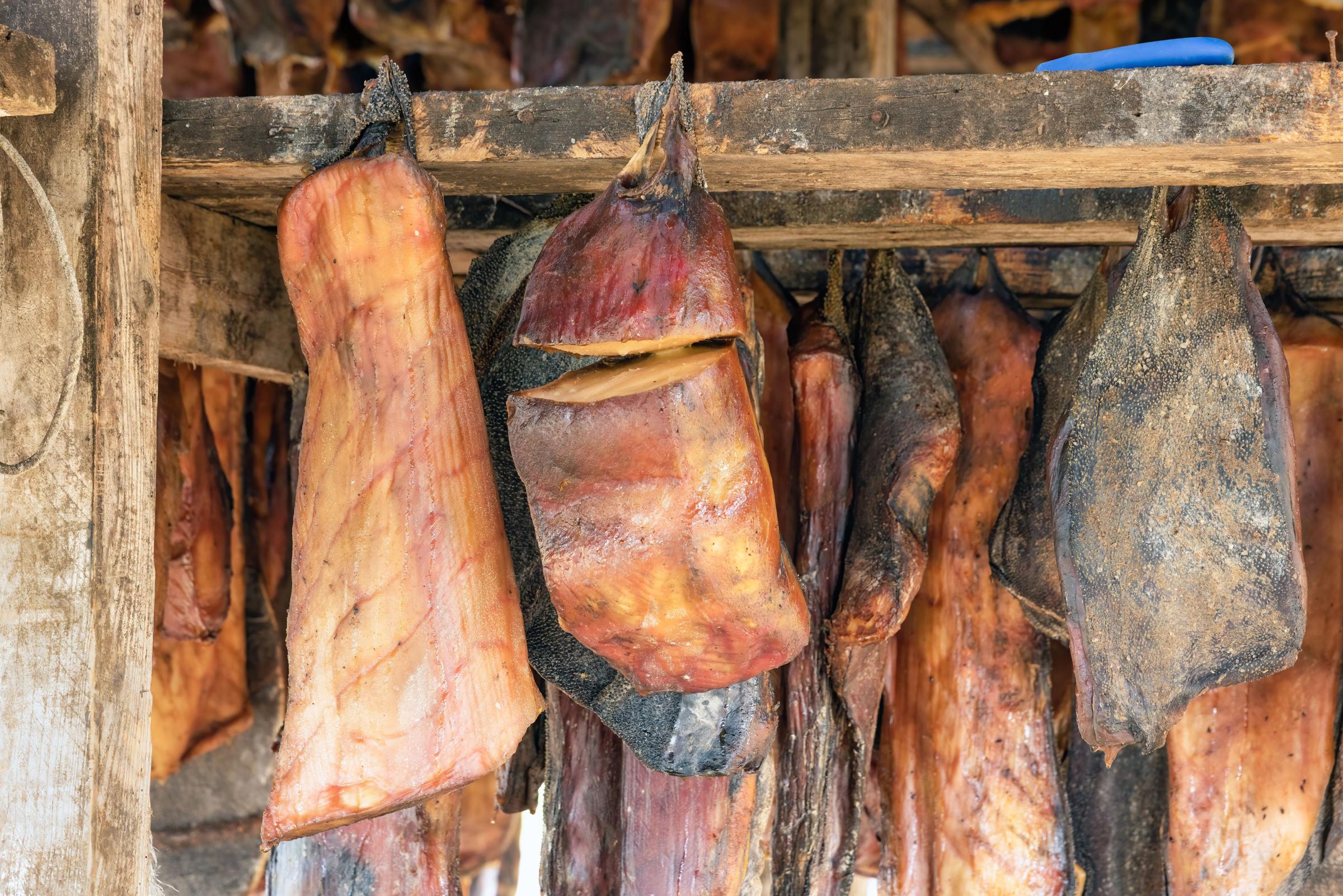 a bunch of meat hanging from a wooden shelf .