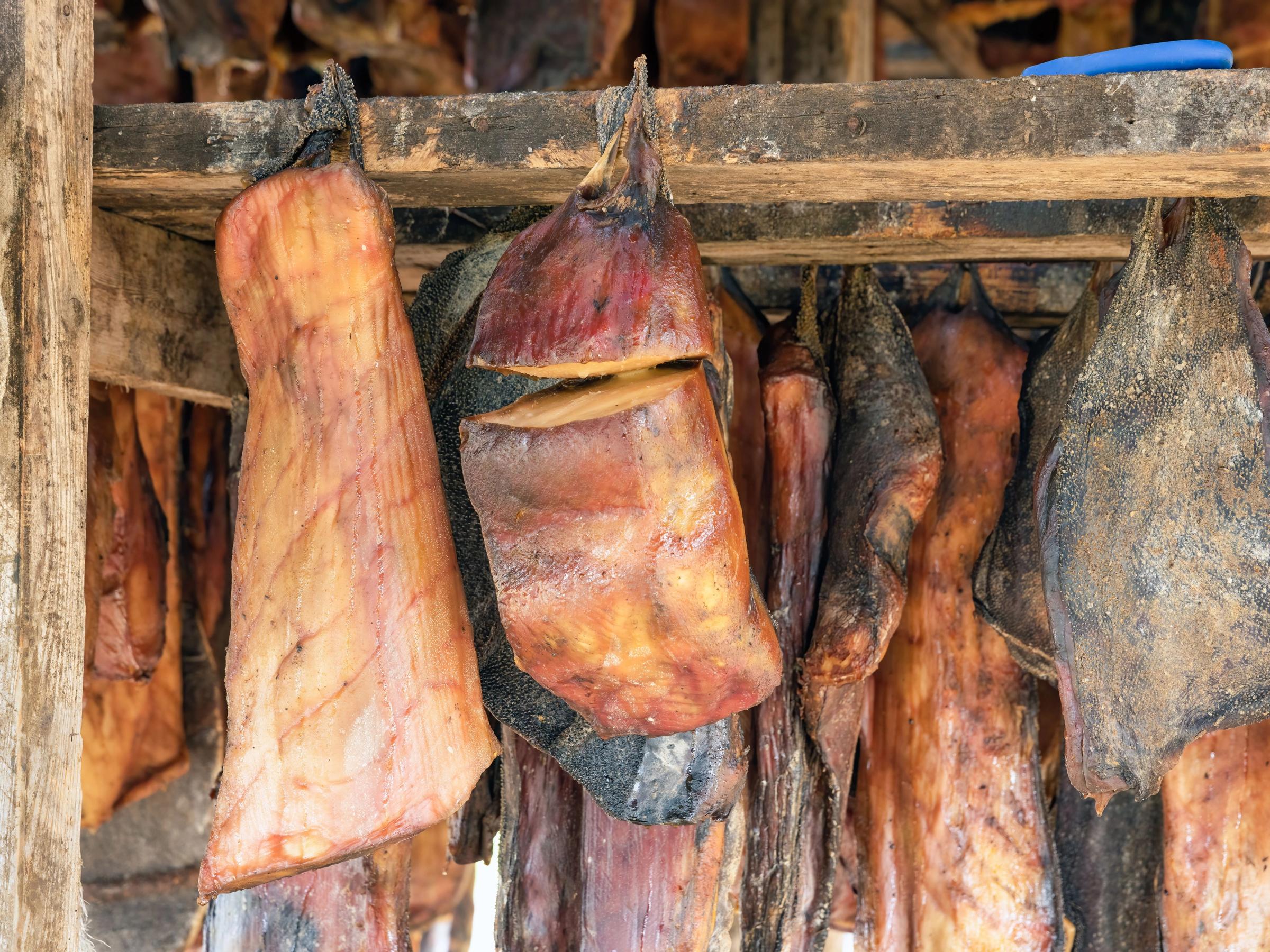 a bunch of meat hanging from a wooden shelf .