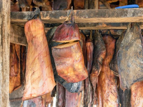a bunch of meat hanging from a wooden shelf .