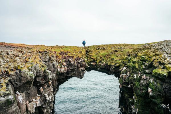 hombre encima de un arco de piedra sobre el mar