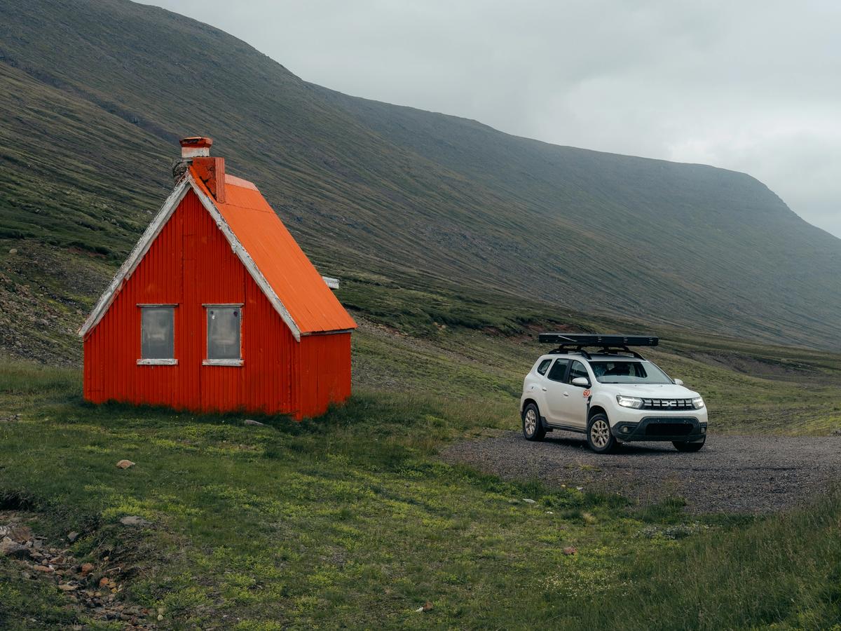 a white car is parked in front of an orange house