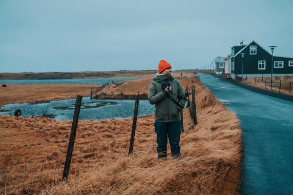 a man is standing in a field holding a camera .
