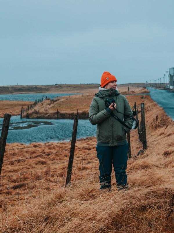 a man is standing in a field holding a camera .