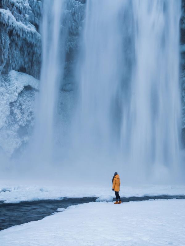 Skogafoss waterfall March Weather in Iceland with a person at Skogafoss waterfall