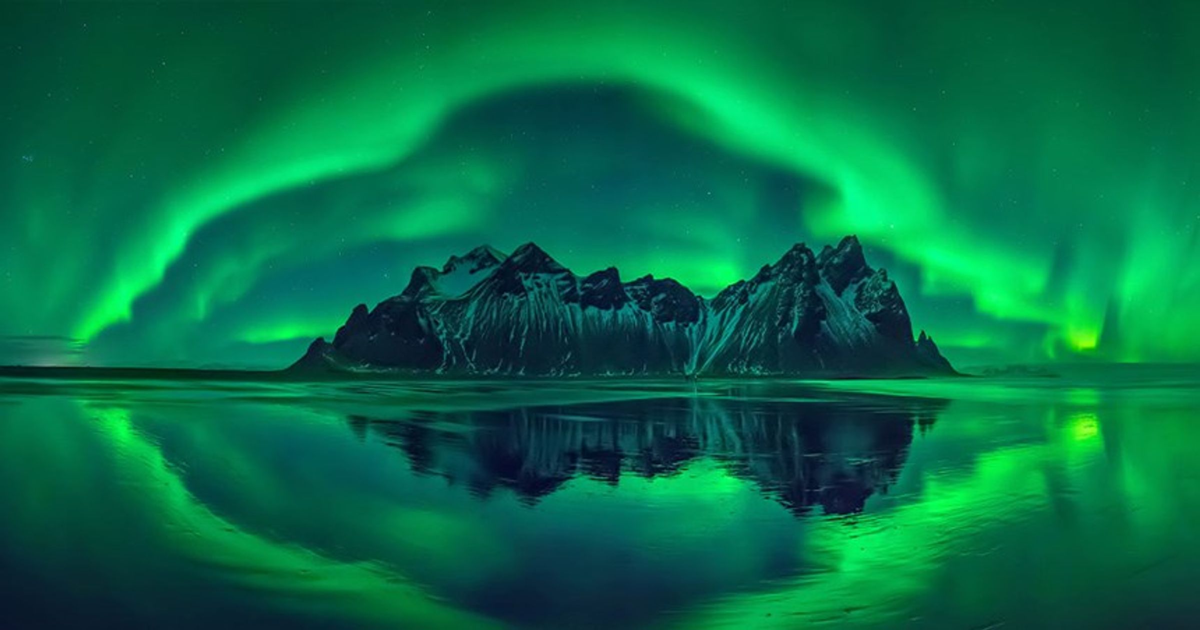 the aurora borealis is reflected in the water of a lake .