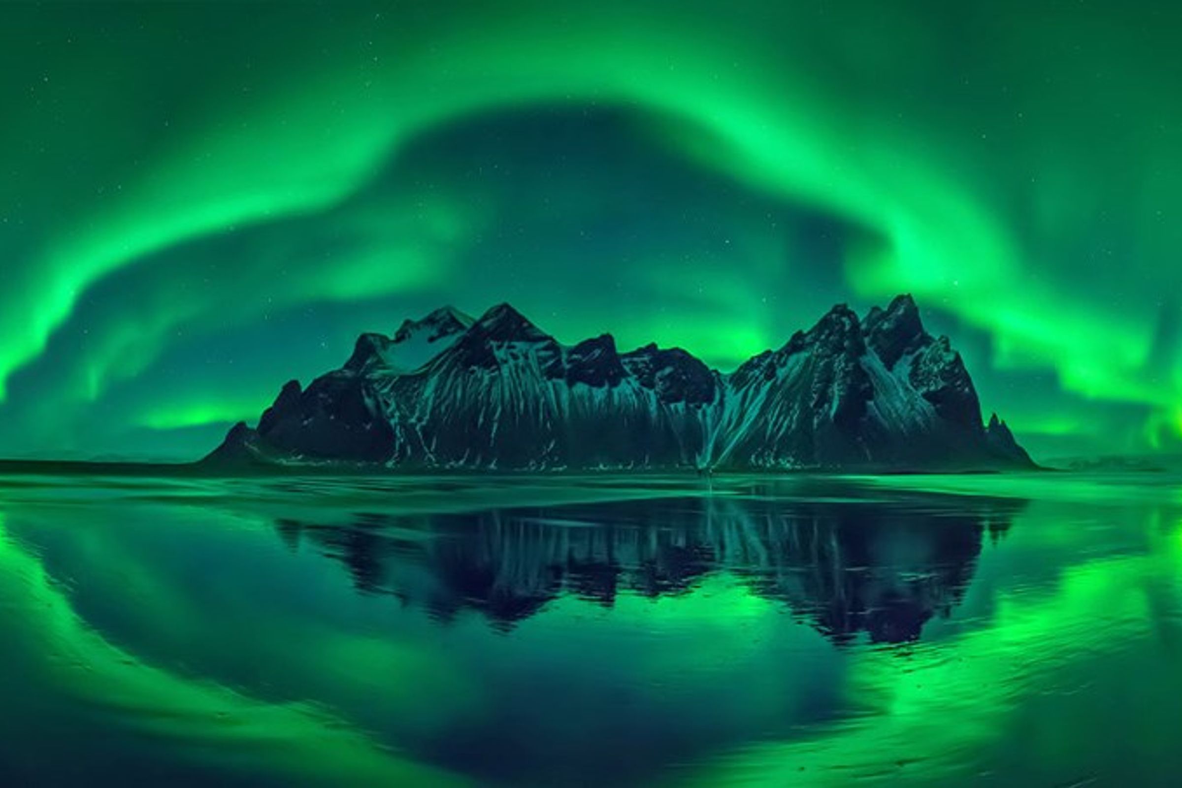 the aurora borealis is reflected in the water of a lake .