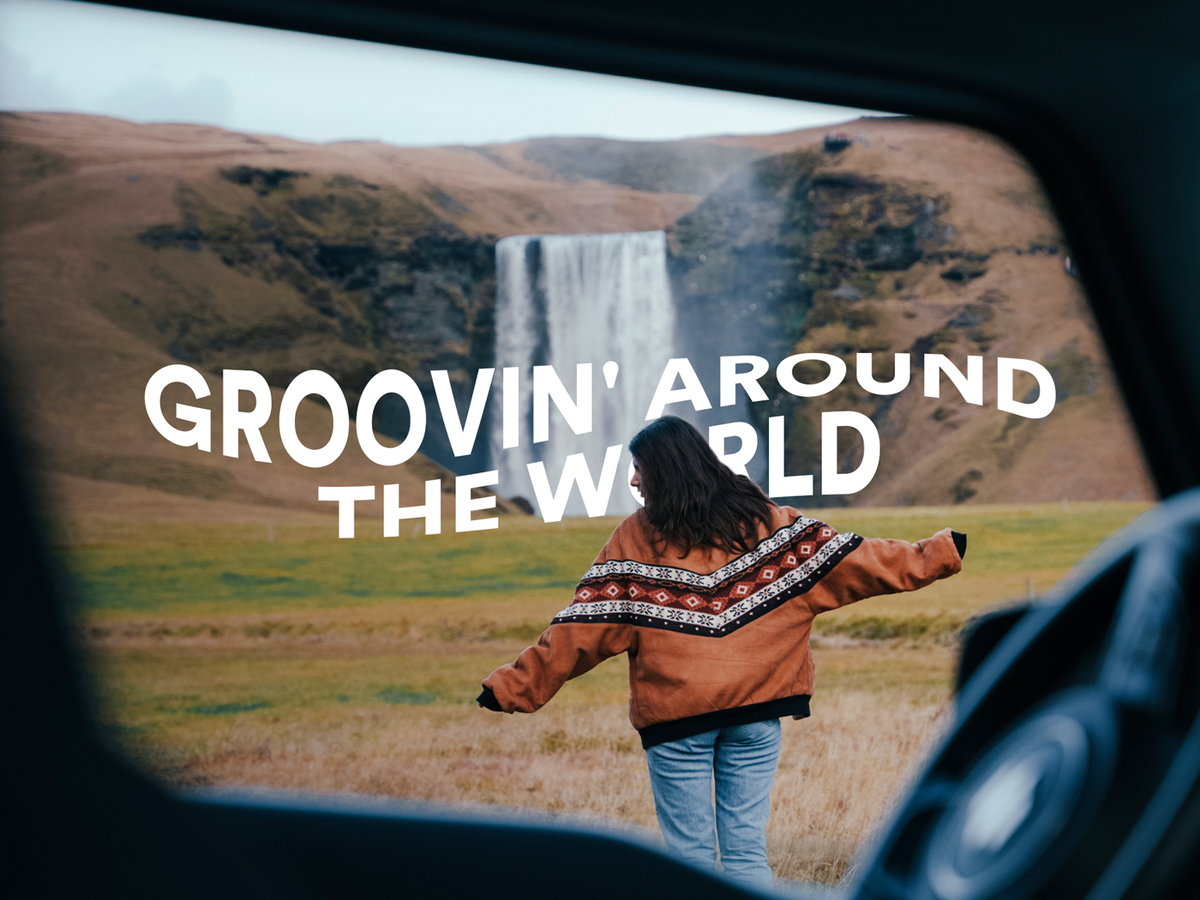 a woman is standing in front of a waterfall with the words groovin around the world above her