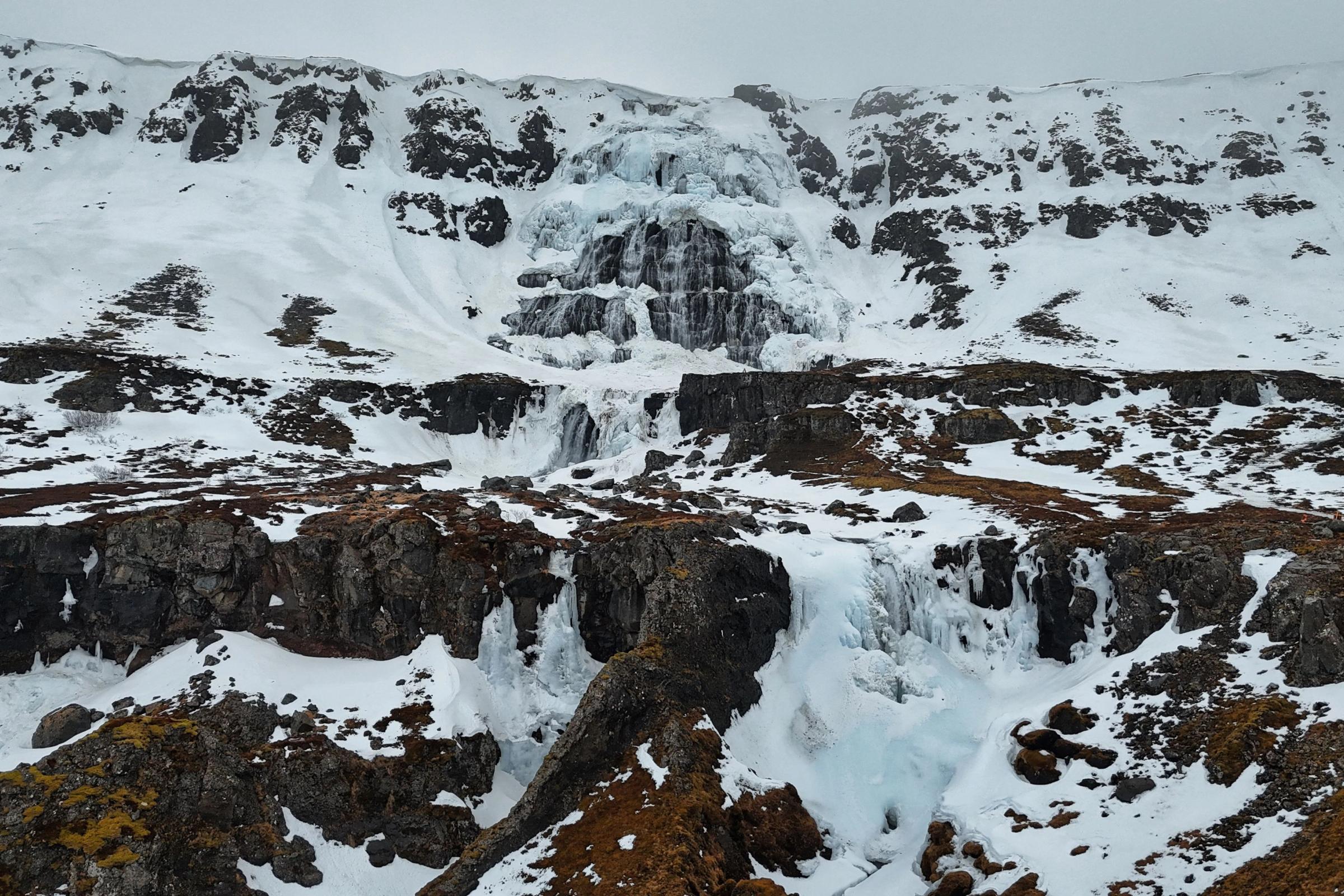 una vista aérea de una cascada en medio de una montaña nevada.