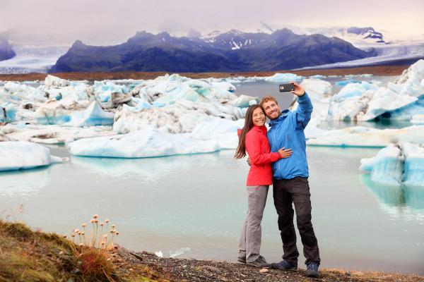 a man and a woman are taking a selfie in front of a glacier .