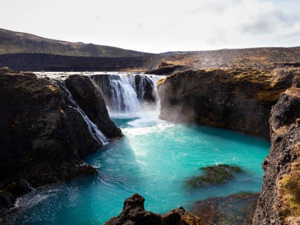 Sigoldufoss waterfall is surrounded by rocks and a large body of water .