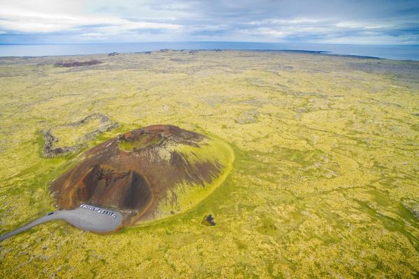 an aerial view of a volcano in the middle of a grassy field .