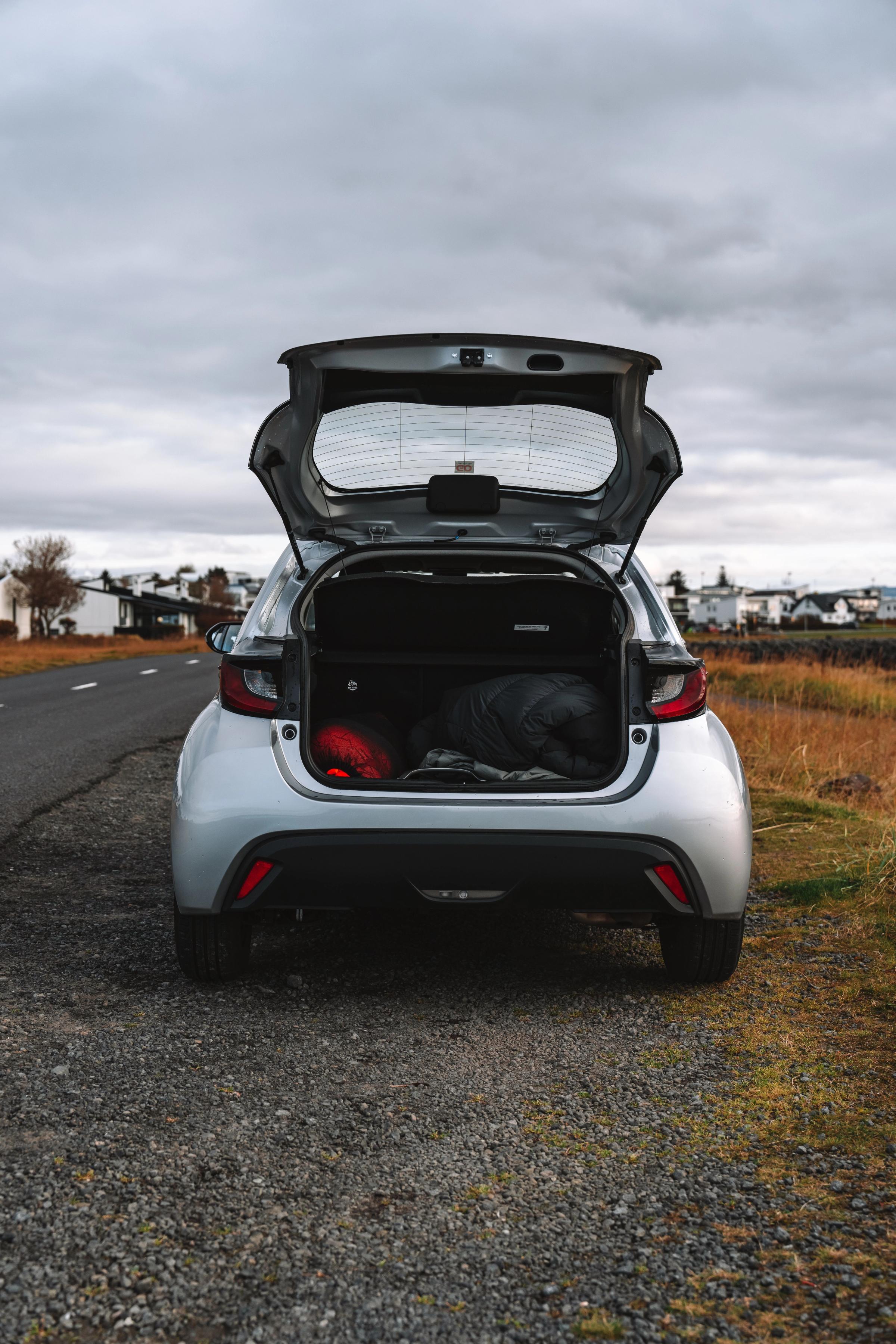 Toyota Yaris open trunk view with luggage parked on a gravel road