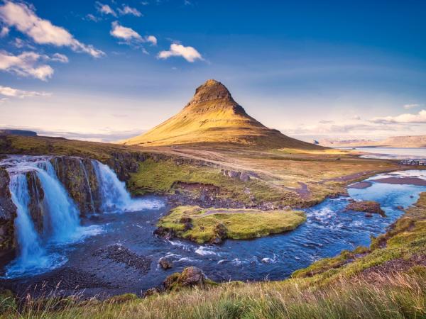 there is a waterfall in the foreground and a mountain in the background .