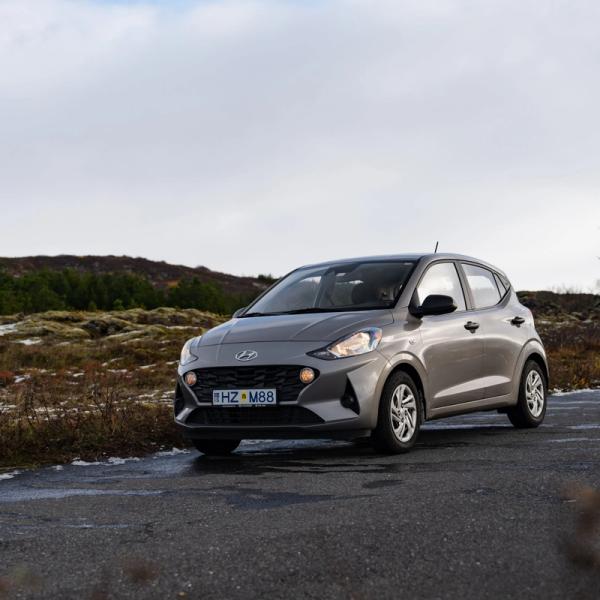 a small silver car is parked on the side of a road .