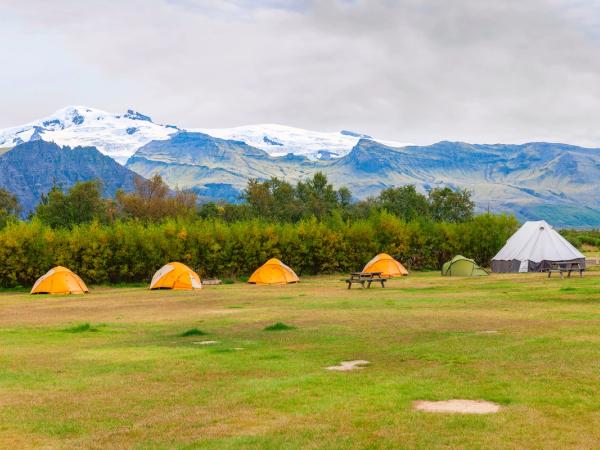 a group of tents are sitting in a grassy field with mountains in the background .