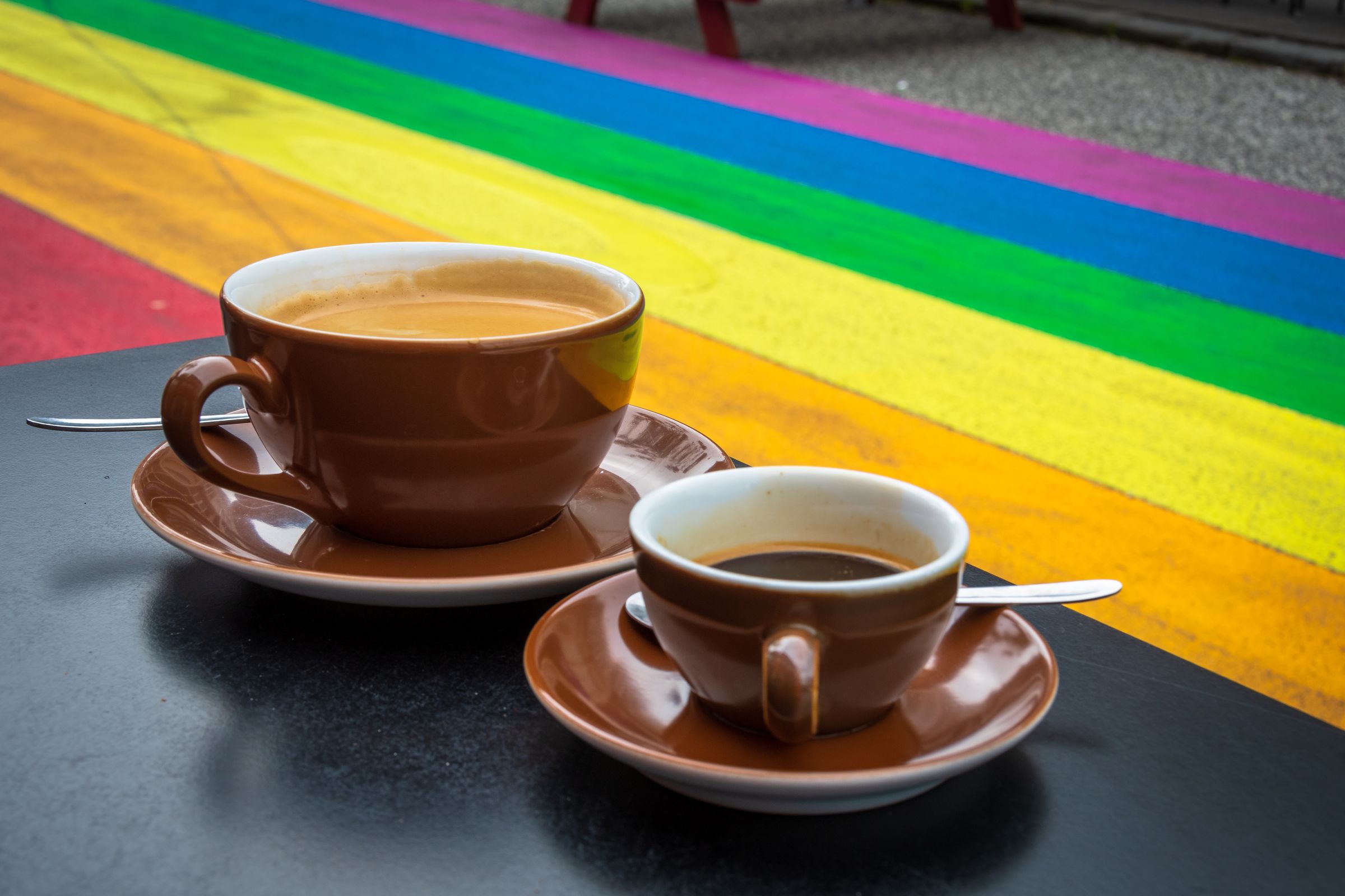 two cups of coffee are sitting on a table in front of a rainbow .