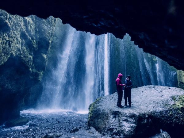 Pareja dentro de una cueva con una cascada