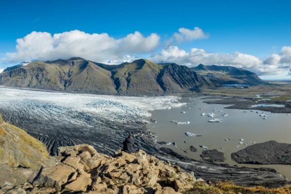une vue panoramique d'un glacier entouré de montagnes et d'un lac .