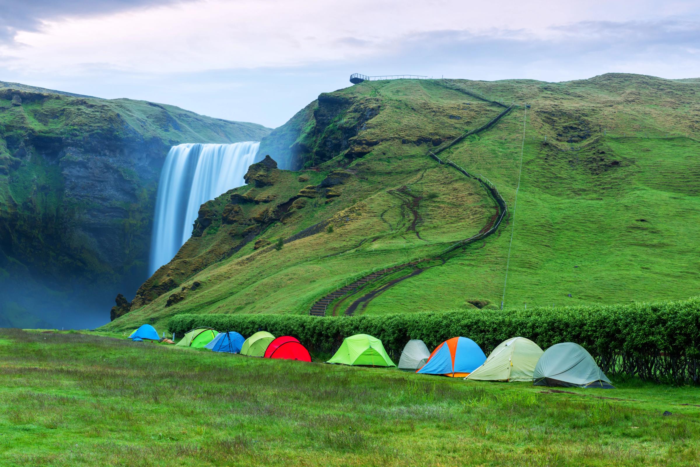 a row of tents are sitting in front of a waterfall .