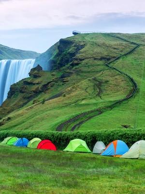 a row of tents are sitting in front of a waterfall .
