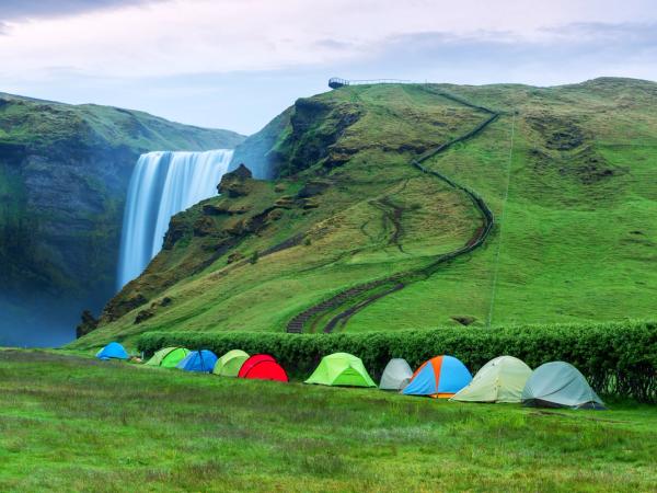 a row of tents are sitting in front of a waterfall .