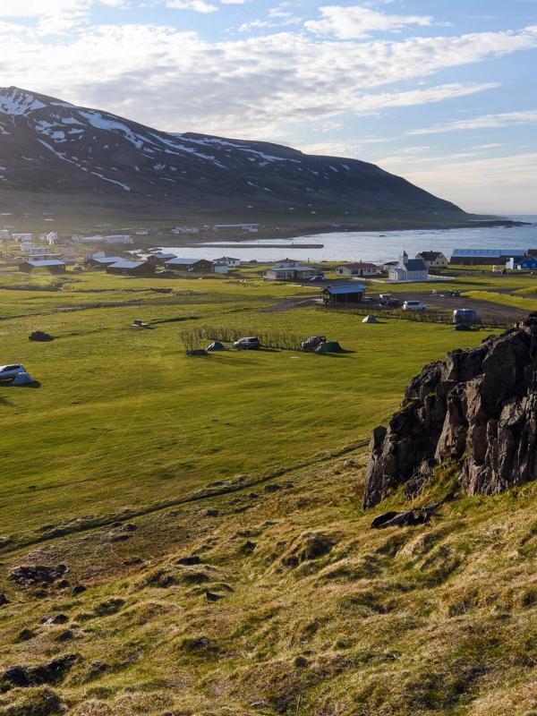 a view of a grassy field with a mountain in the background and a body of water .