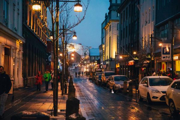 a city street at night with cars parked on the side of it and people walking down it .Reykjavik rainy night downtown in Iceland