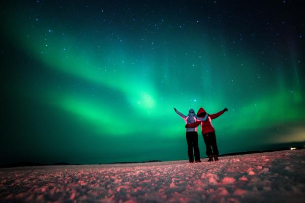 dos personas abrazadas bajo la Aurora Boreal