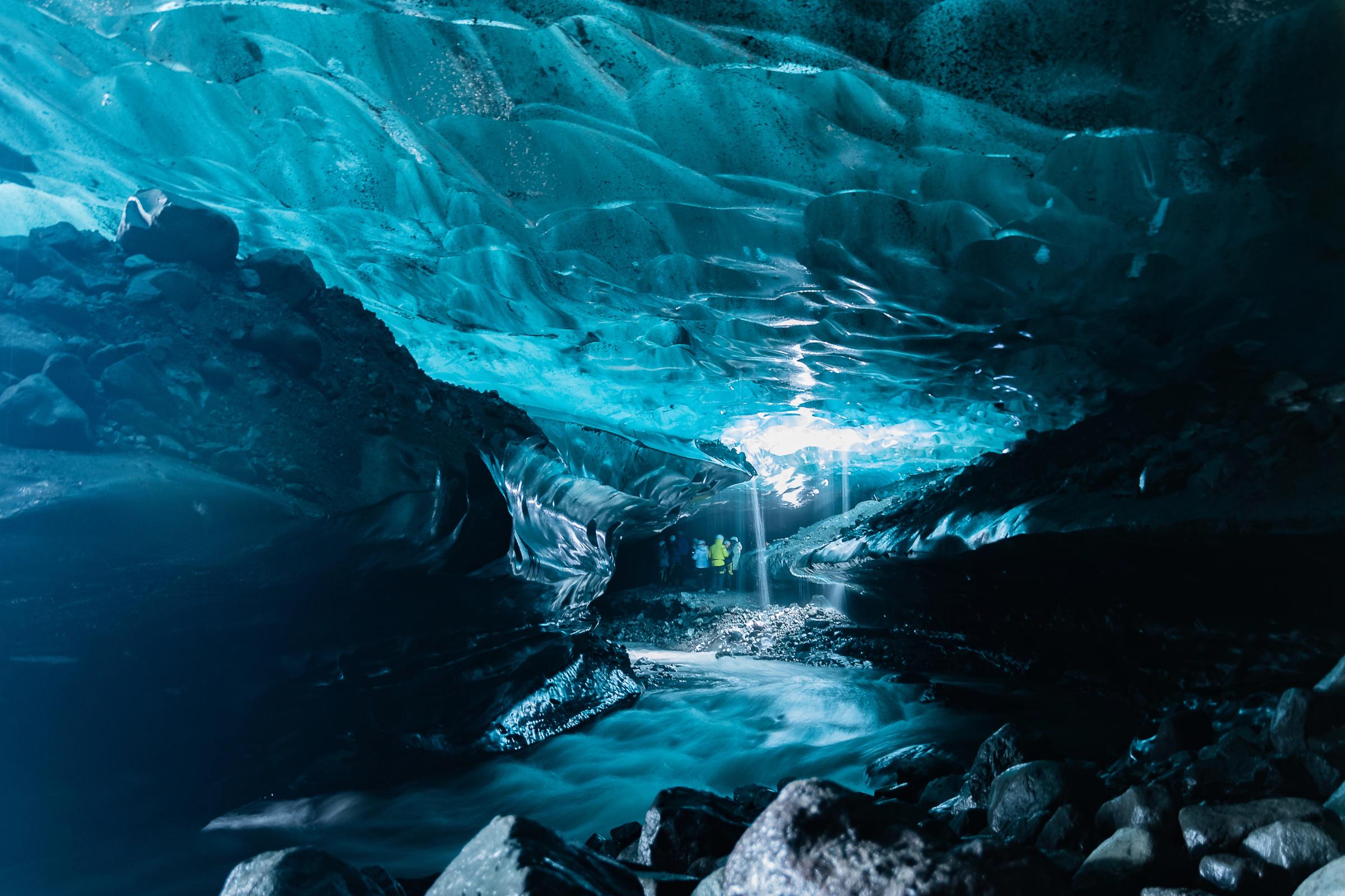 a group of people are standing inside of an ice cave .