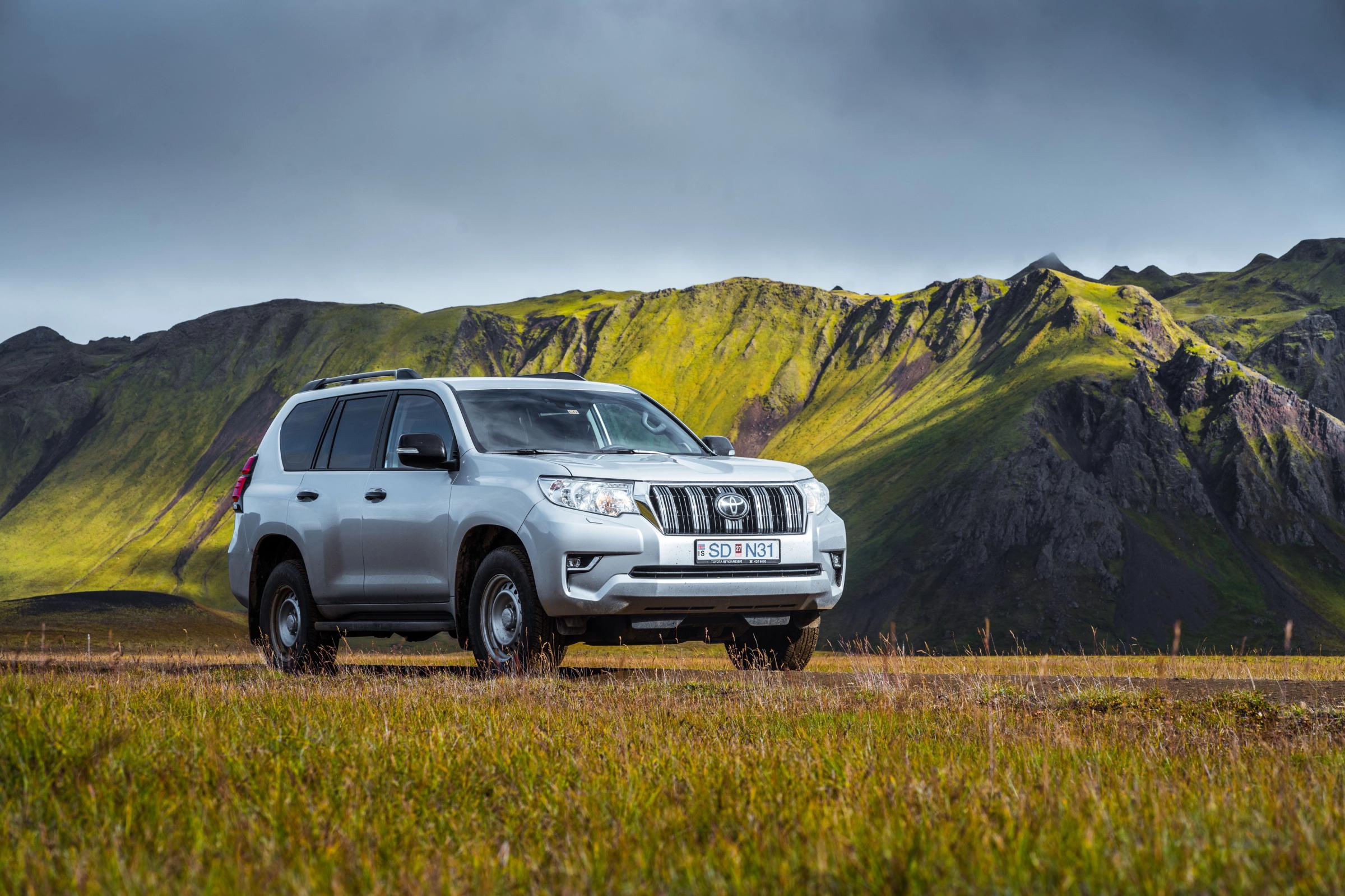 Land Cruiser Highland View Toyota Land Cruiser in schräger Frontansicht, auf einer Wiese unterhalb eines moosbewachsenen Bergrückens geparkt