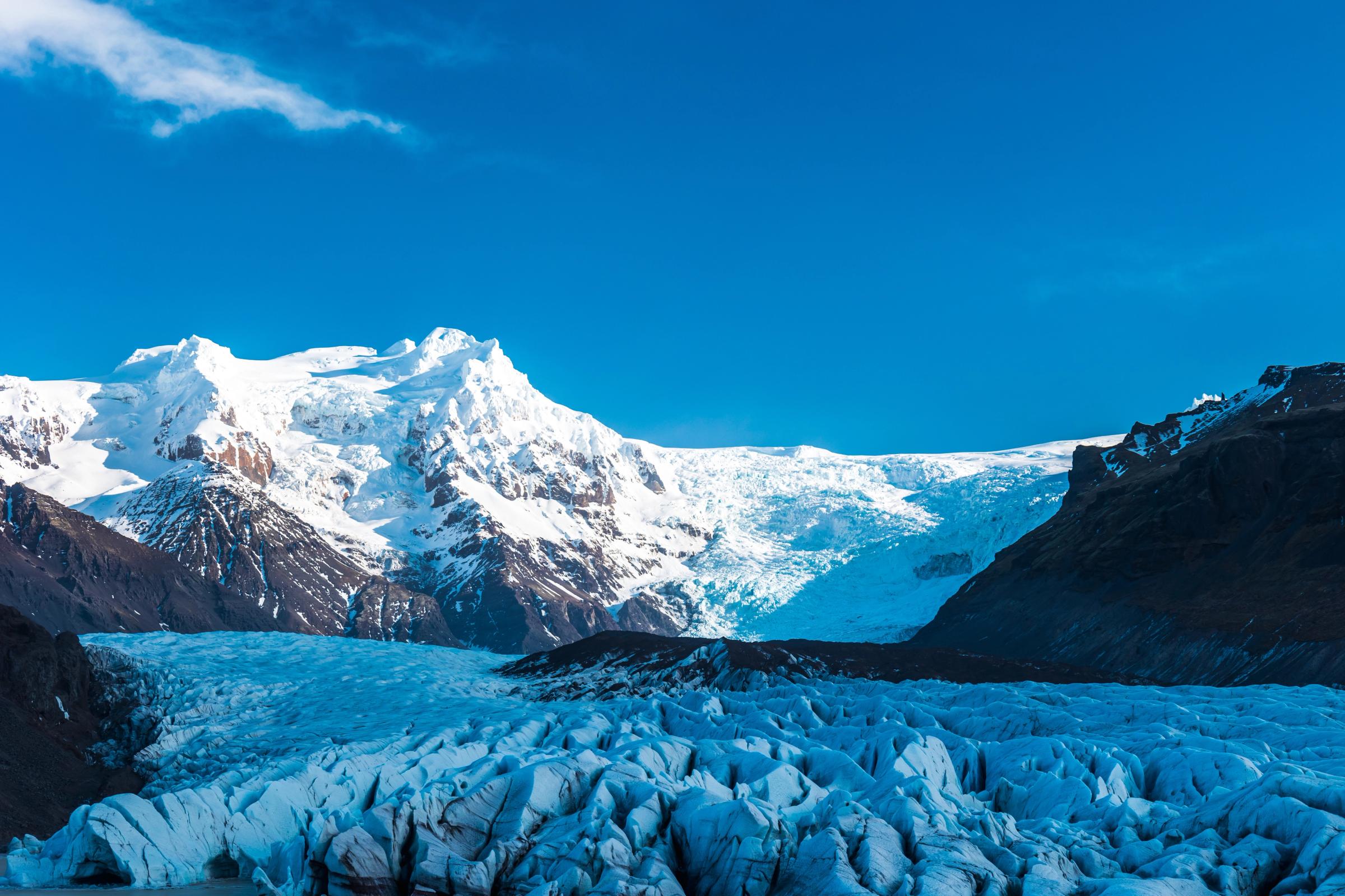Un glaciare enorme al lado de montañas nevadas