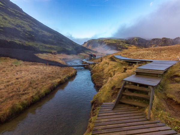 río corriendo entre dos montañas con un camino de madera al lador