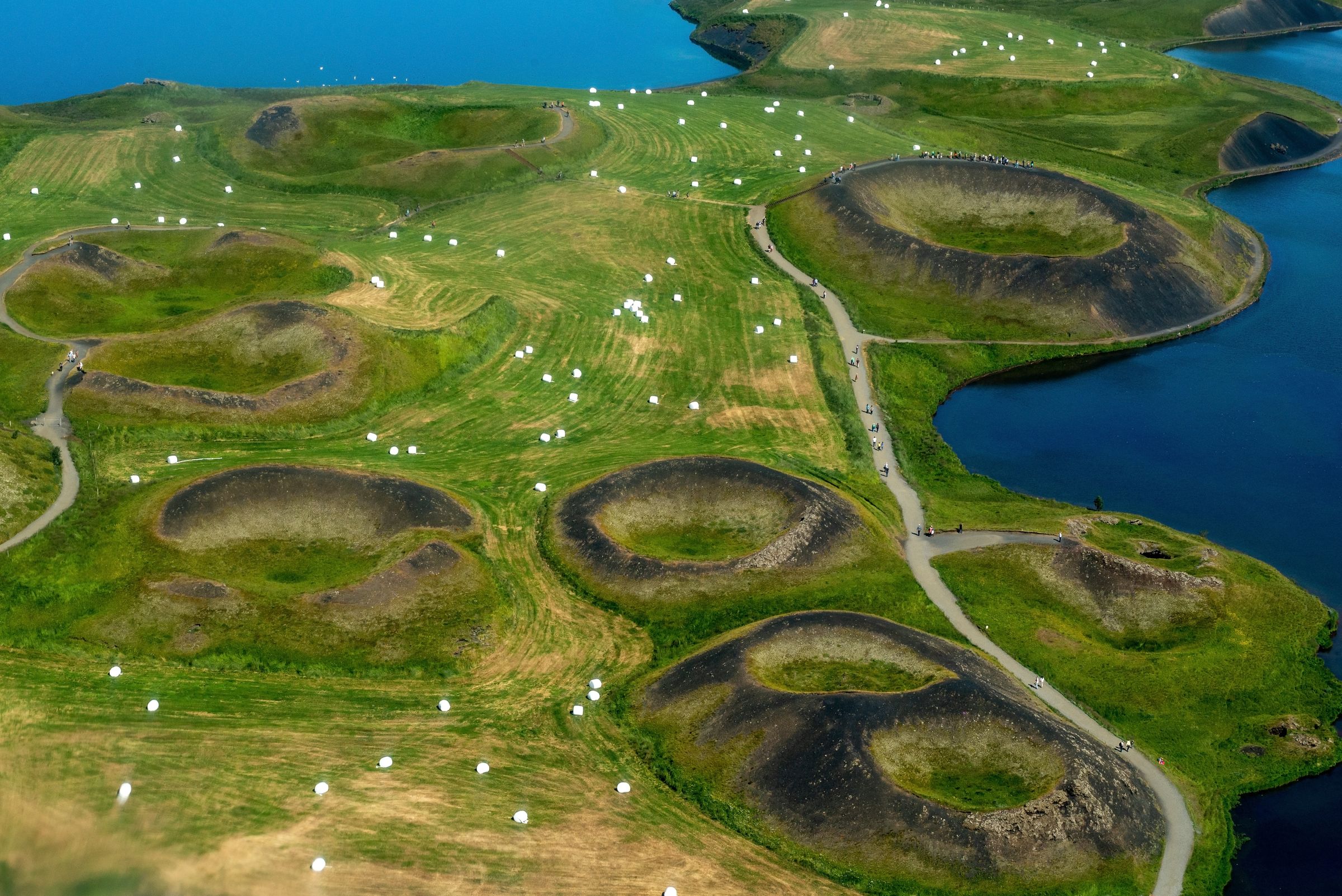 an aerial view of a lush green field with a lake in the background at lake myvatn in north iceland.