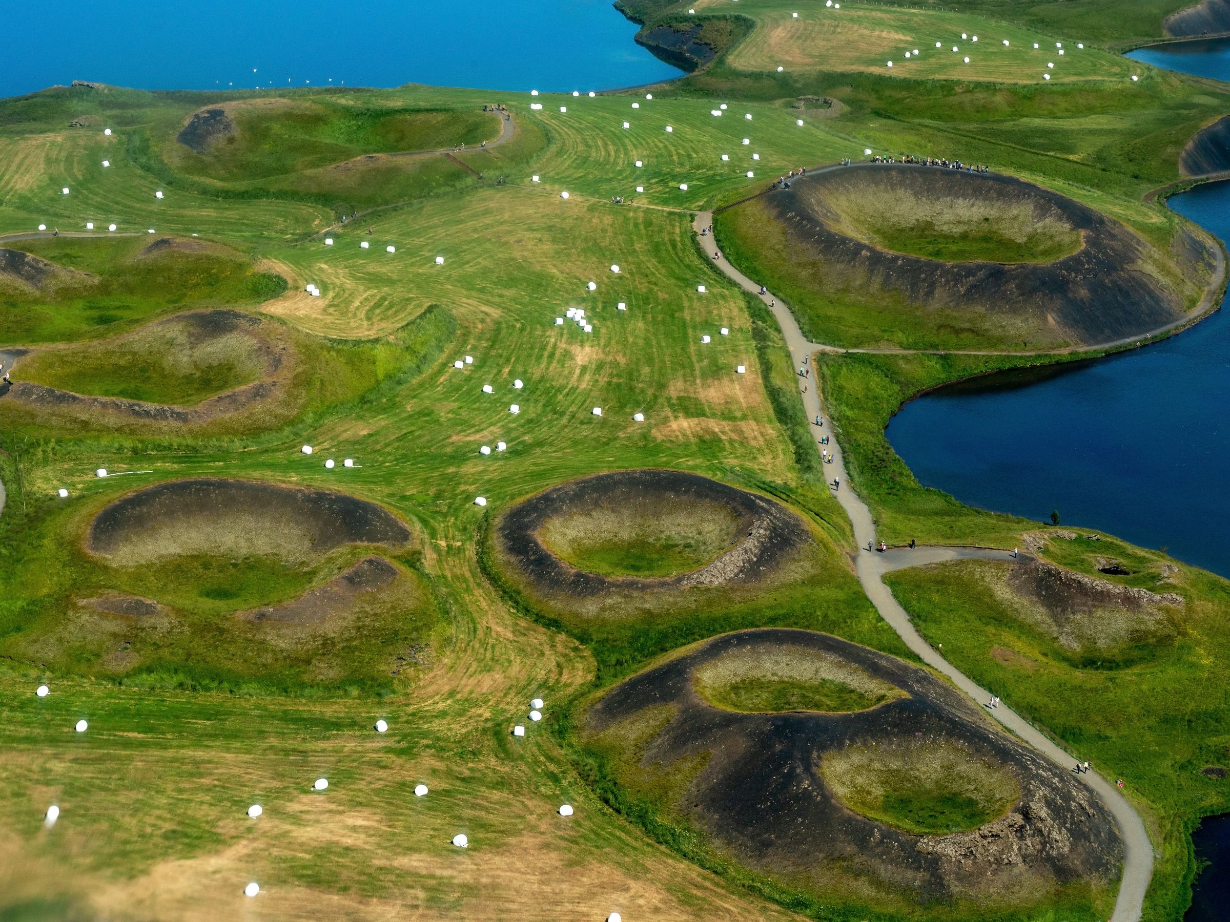 an aerial view of a lush green field with a lake in the background at lake myvatn in north iceland.