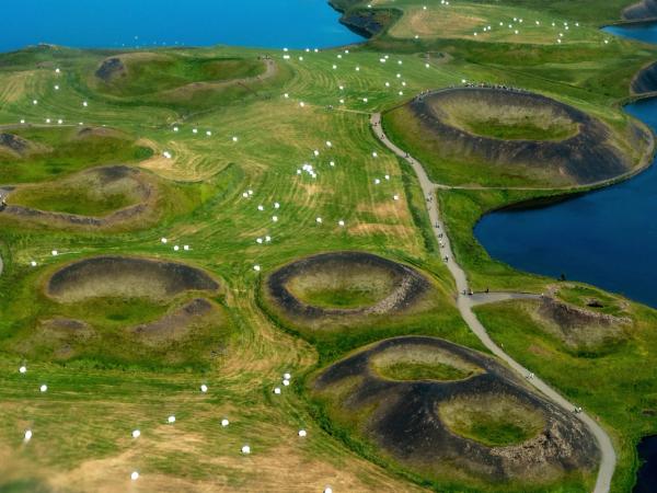 an aerial view of a lush green field with a lake in the background at lake myvatn in north iceland.