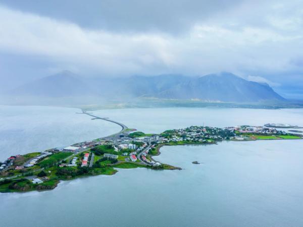 una vista aérea de una pequeña isla en medio de un gran cuerpo de agua con montañas en el fondo.
