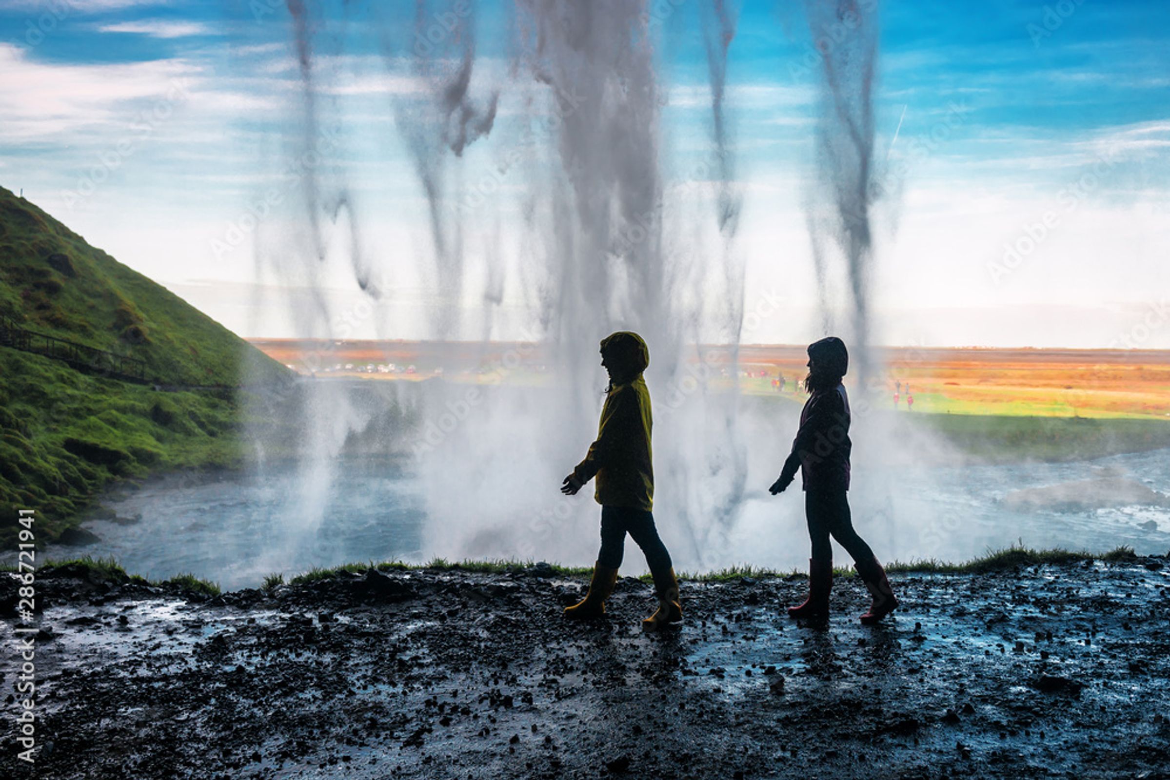 two people walking behind a waterfall